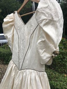 "Beautiful vintage 80s silk bridal dress. Victorian style with puff sleeves, embroidered panels and floral decorations. Zips up at the back. Ivory silk with brown piping and silk flowers. Very good clean condition. Lovely train with embroidered panels. Vintage size 14 probably nearer a 12 please see measurements Measured flat Chest 19\" Pit to hem 9\" Waist 15\" Skirt 43\"" Elegant Vintage Puff Sleeve Wedding Dress, Silk Vintage Victorian Dress For Wedding, Vintage Puff Sleeve Dress For Wedding, Silk Bridal Dress, Embroidered Jumpsuit, Abstract Dress, Floral Decorations, Ivory Silk, Dress Purchase