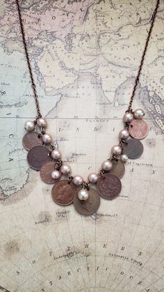 a necklace with coins and pearls hanging from it's sides on top of a map