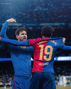 two soccer players in blue and red uniforms are hugging each other on the field at a stadium