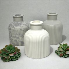 three white vases sitting next to each other