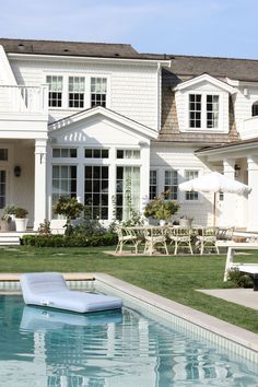 an inflatable mattress sitting on the edge of a pool next to a house