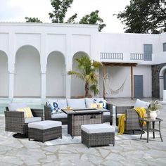 an outdoor patio area with wicker furniture and yellow throw pillows on the cushions, near a pool