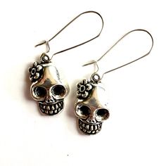 Discover your new favorite earrings today! These unique, stylish, and affordable silver tone skull earrings are the perfect gift for someone special or for treating yourself. Handcrafted with brass metal alloy, they have a gothic flair that sets them apart. Add a touch of Mexico to your outfit with these flowered skull earrings, inspired by the Day of the Dead. Perfect for women and girls, these lever back ear wires make a stunning addition to any jewelry collection. Don't miss out on this amazi Silver Skull Earrings For Halloween, Skull-shaped Metal Earrings, Bohemian Skull Earrings For Gifts, Gothic Skull Metal Earrings, Metal Skull Jewelry With Skull Print, Gothic Sterling Silver Skull Earrings, Nickel Free Skull Jewelry For Day Of The Dead, Nickel-free Skull Jewelry For Day Of The Dead, Silver Skull Earrings With Skull Print