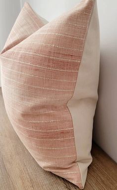 a pink pillow sitting on top of a wooden floor next to a white wall and door