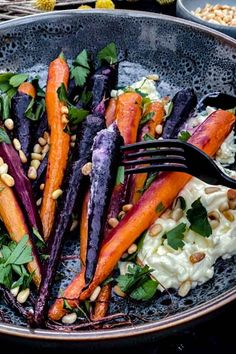 carrots and other vegetables are in a bowl with a fork on the side, along with chickpeas