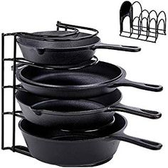 black pots and pans are stacked up in a rack