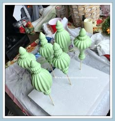 three green cake pops sitting on top of a white counter next to other food items