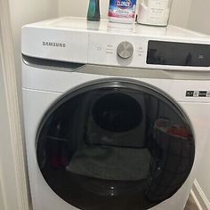 a white washer sitting on top of a dryer next to a bottle of cleaner