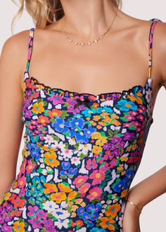 ELIGIBLE FOR RETURNS OR EXCHANGES Start your vacation with a beach view in the Renoir's Terrace Ruffle One-Piece Swimsuit! This floral inspired pattern is featured in an array of spring colors to bring charisma as you dip your toes into the sand. The bust features a a small ruffle trim and sweet bow for a feminine touch. Adjustable strap tie details are found at the shoulder for better support! Style # WMKC09047 Imported 80% Nylon, 20% Spandex Model is 5 ft 9 inches; Bust: 32", Waist: 23.5", Hip Summer Tropical Print Swim Dress For Poolside, Summer Swim Dress With Tropical Print For Poolside, Summer Style Tropical Print Swim Dress For Poolside, Beachy Printed Swimwear For Summer Parties, Sleeveless Ruffle Swim Dress For Beach Season, Multicolor Sleeveless Swim Dress For Poolside, Sleeveless Multicolor Swim Dress For Poolside, Multicolor Sleeveless Swim Dress For Summer, Spring Beachwear Tankini For Summer Parties