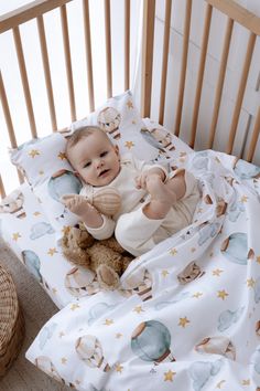 a baby in a crib holding a teddy bear