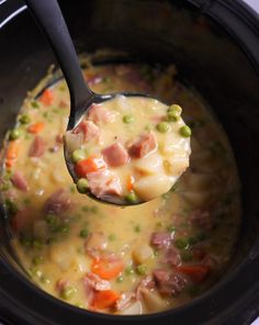 a spoon full of soup with peas, ham and carrots in it's crock pot