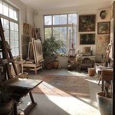 an artist's studio with lots of easels, paintings and plants in the window