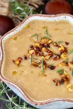 a white bowl filled with food sitting on top of a wooden table next to nuts