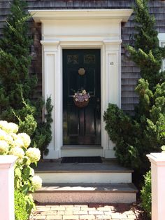 the front door of a house with potted plants and flowers on it's step