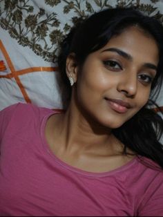 a woman laying in bed smiling at the camera