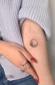 a woman's arm with a small globe tattoo on the left side of her arm