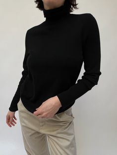 Lovely finely knit turtleneck sweater in an onyx tone. The sweater is a staple in the wintertime, perfect for layering under a favorite blazer, or styled under a crewneck sweater. Material not listed, assuming cotton blend Recommended for size xs-m, depending on the desired fit. Modeled on small frame. Please refer to the measurements listed below: Measures approximately: 16" shoulder to shoulder / 36" bust / 24" sleeve length / 23" shoulder to hemline One inch spot of distressing at the shoulde Classic Stretch Cashmere Tops, Stretch Cashmere Sweater In Solid Color, Stretch Solid Color Cashmere Sweater, Fall Everyday Turtleneck Tops, Chic Cashmere Turtleneck, Black Turtleneck For Fall Workwear, Black Turtleneck For Workwear In Fall, Black Turtleneck For Fall Layering, Trendy Black Knit Turtleneck