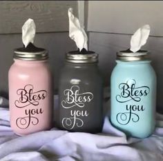 three painted mason jars sitting on top of a bed