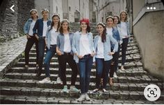 a group of young women standing next to each other on top of steps in front of buildings