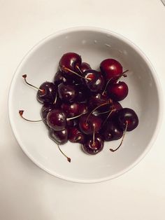 a white bowl filled with cherries on top of a table