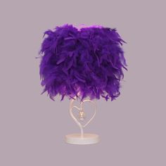 a purple feather lamp on a white stand with a heart shaped light in the middle