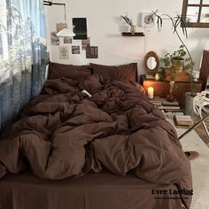 an unmade bed with brown sheets in a bedroom next to a window and potted plants