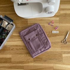 the sewing machine is next to some crafting supplies on the wooden floor with scissors and thread