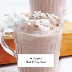 whipped hot chocolate in a glass mug with marshmallows on top and the words whipped hot chocolate above it