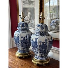 two blue and white vases sitting on top of a table next to a mirror