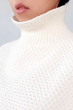 a woman with black hair wearing a white turtle neck sweater and glasses on top of her head