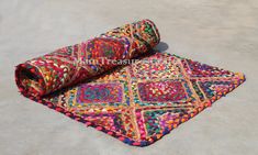 a multicolored rug is rolled up on the ground with it's end laying down