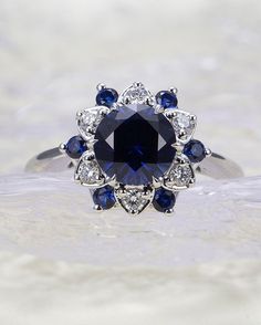 a blue and white diamond ring sitting on top of a table