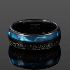 a ring with blue and black inlays on the inside, sitting on a reflective surface