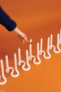 a person lighting candles in the shape of letters on an orange surface with one hand holding a lit match