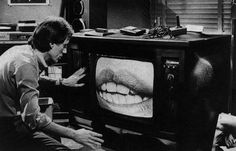 a man sitting in front of a tv with teeth on it