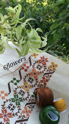 two spools of thread sitting on top of a table cloth next to some flowers