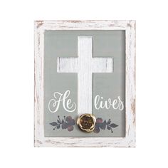 a wooden frame with a white cross and flowers on the bottom that says he lives