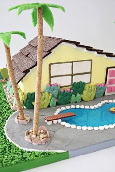 a cake that looks like a house with a pool in the front yard and palm trees