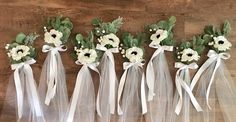 six bridesmaid's bouquets with white flowers and greenery tied together