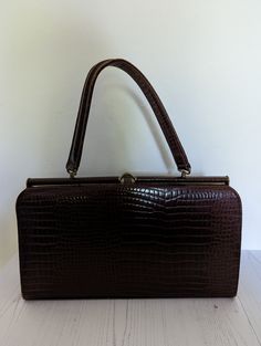 A lovely vintage handbag from the collectible MacLaren of Norwich, England. Made from genuine leather, this bag has a carry handle and is in a traditional boxy shape The handbag is made from brown leather in a snakeskin style. There in one large internal compartments with a smaller zip pocket on the inside and a pouch on the opposite side. The handbag fastens with a top clasp which is still very strong The handbag measures approx 33cm x 19cm x 7cm. The strap is 34cm long. There are some marks to the bag as the photos show but generally it is in very good vintage condition handbag and dates from the 1960s Ideal bag to complete a vintage outfit Brown Rectangular Box Bag With Detachable Handle, Brown Rectangular Box Bag With Carry Handle, Brown Rectangular Shoulder Bag With Detachable Handle, Brown Shoulder Bag With Detachable Handle, Classic Evening Satchel In Rectangular Case, Classic Evening Satchel In Rectangular Shape, Classic Brown Box Bag With Top Handle, Classic Evening Satchel With Rectangular Case, Classic Brown Box Bag With Top Carry Handle