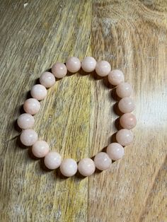 a pink beaded bracelet sitting on top of a wooden table