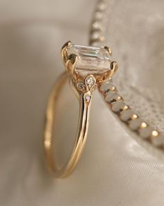 an engagement ring with a baguette cut diamond in the center on a white cloth