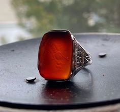 A wonderful Roman god ring for all sexes! This ring features a burnt orange carnelian expertly carved with a depiction of the Roman god Mercury. Among other things, Mercury was the god of good fortunate and wealth (perfect for a graduate or new entrepreneur), and was considered the most clever of all the Roman gods. Crafted during the 1920's the ring is further embellished with deep hand engraving all around the gallery and shoulders. This ring bears the makers mark of White, While, and Warner a Formal Carnelian Signet Ring With Polished Finish, Vintage Carnelian Signet Ring For Formal Occasions, Art Deco Intaglio Rings As Gift, Formal Sterling Silver Engraved Ring With Intaglio, Formal Sterling Silver Intaglio Engraved Ring, Sterling Silver Intaglio Engraved Ring For Formal Occasions, Formal White Gold Signet Ring With Intaglio, White Gold Signet Ring With Intaglio For Formal Events, White Gold Signet Ring With Intaglio For Formal Occasions