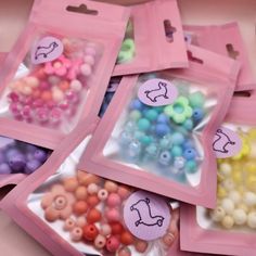 several bags filled with different colored beads on top of a table next to each other