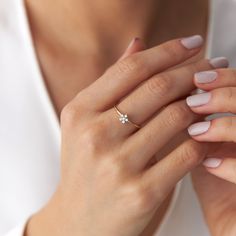 a woman's hand with a diamond ring on her left hand, wearing a white shirt