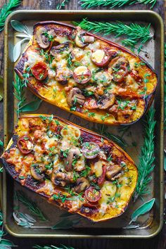 two delicacy squash halves with mushrooms, tomatoes and herbs on a baking sheet