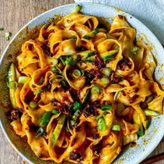 a bowl filled with pasta and vegetables on top of a wooden table