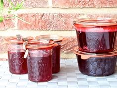 jars filled with red liquid sitting on top of a white tile floor next to a brick wall