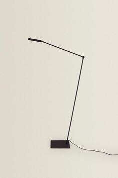 a black floor lamp on a white wall