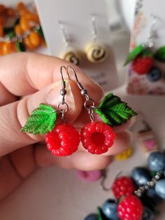 a pair of earrings with raspberries and leaves hanging from it's hooks